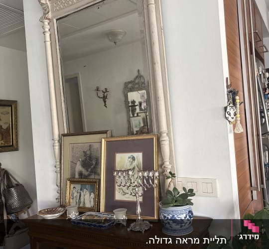 מראה גדולה על קיר עם חפצי נוי על מדף